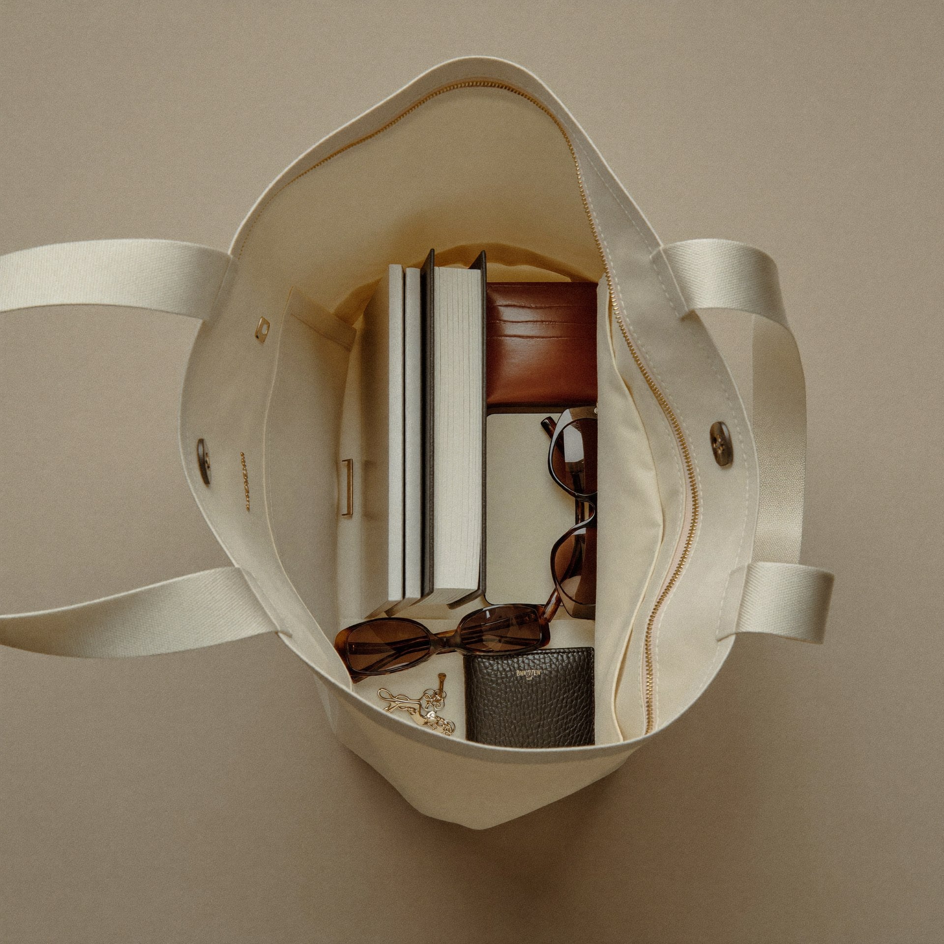 The Tote open showing organized interior with laptop, book, wallet, phone and essentials