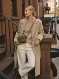 Woman leaning NYC brownstone golden hour with The Mini Slouch crossbody in Olive premium nylon by Bowryn — warm beige editorial